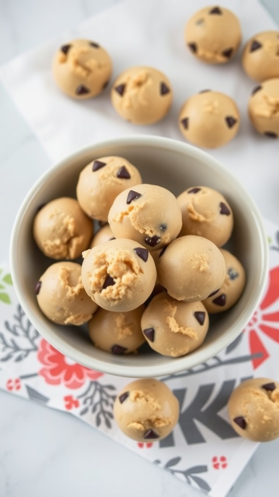 A bowl filled with no-bake cookie dough bites, some scattered around on a colorful napkin.